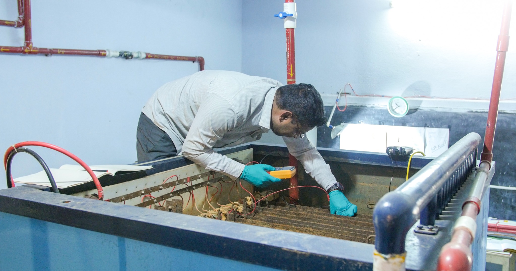 Researcher measuring an electrode array in an electrolysis tank