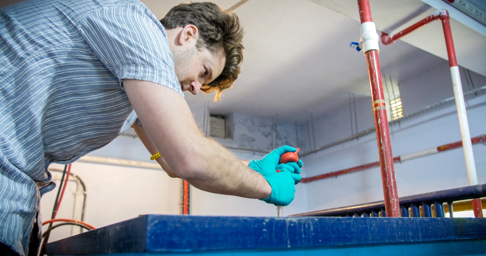 Researcher collecting a sample from an electrolysis tank